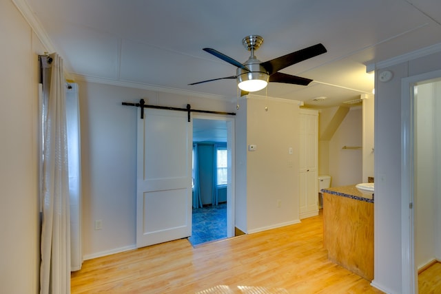 kitchen featuring light hardwood / wood-style flooring, a barn door, crown molding, and ceiling fan