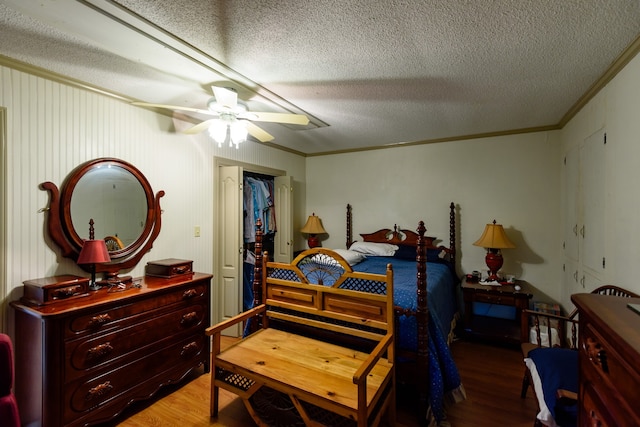 bedroom with a textured ceiling, a closet, ceiling fan, hardwood / wood-style flooring, and ornamental molding