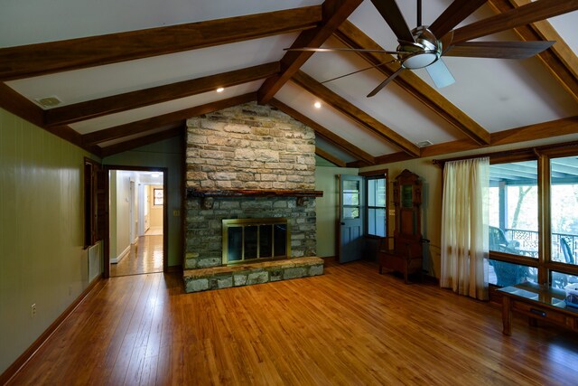 unfurnished living room featuring vaulted ceiling with beams, a stone fireplace, wood-type flooring, and ceiling fan