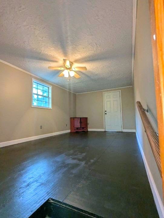 unfurnished living room featuring ceiling fan, crown molding, and a textured ceiling