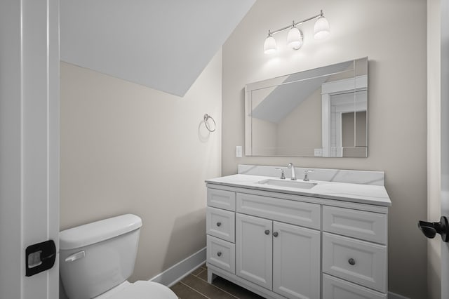 bathroom with vanity, vaulted ceiling, toilet, and tile patterned flooring