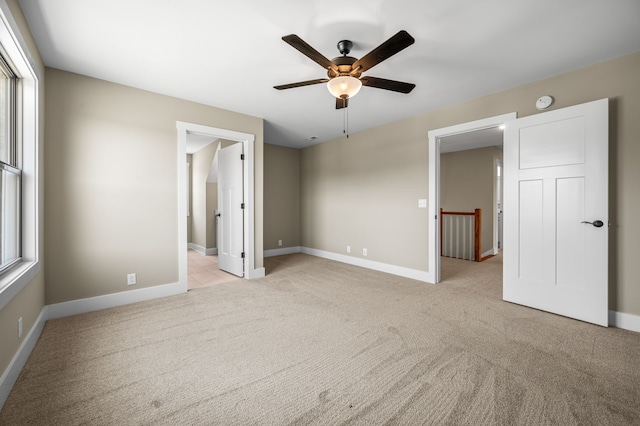 unfurnished bedroom featuring multiple windows, light colored carpet, and ceiling fan