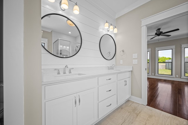 bathroom featuring ceiling fan, wood-type flooring, ornamental molding, vanity, and an enclosed shower