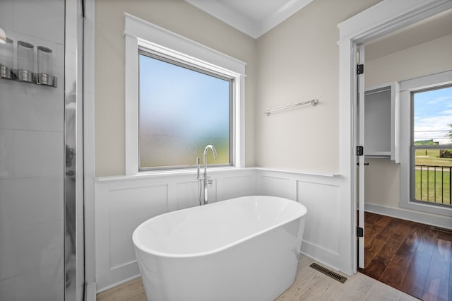 bathroom with crown molding, wood-type flooring, and a washtub