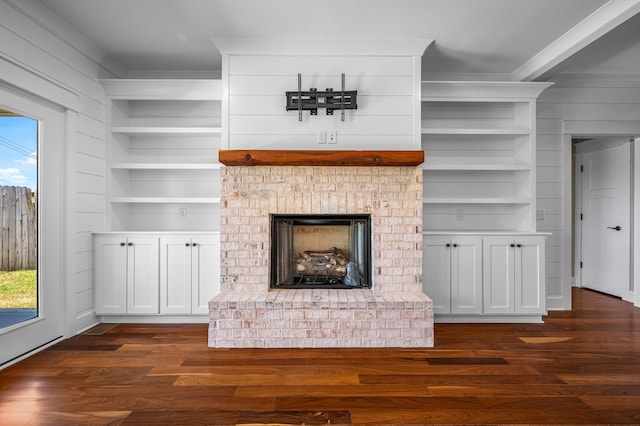 unfurnished living room featuring dark wood-type flooring, a brick fireplace, and built in shelves