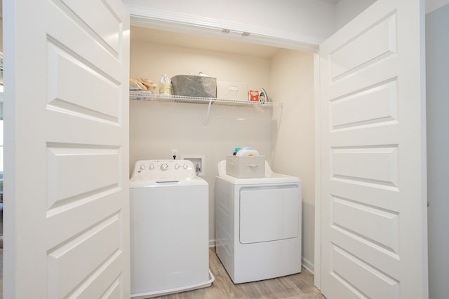 washroom with washing machine and dryer and light wood-type flooring