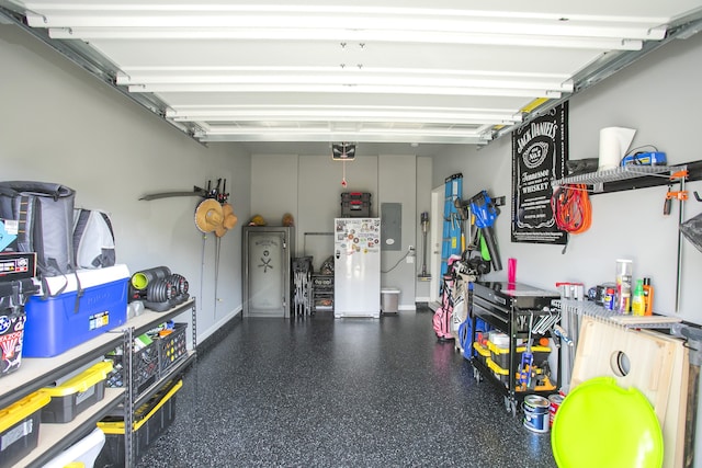 garage featuring a garage door opener, electric panel, and white refrigerator