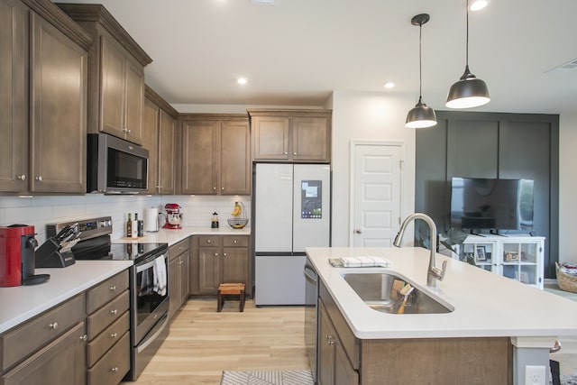 kitchen featuring light hardwood / wood-style floors, stainless steel appliances, tasteful backsplash, and an island with sink