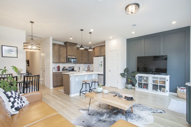 living room with sink, a notable chandelier, and light wood-type flooring