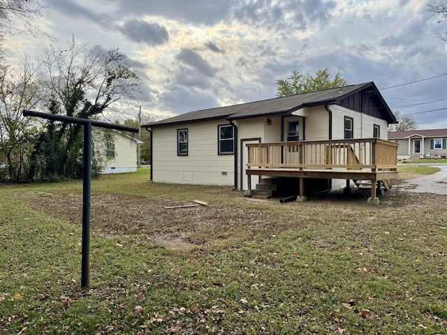 back of property featuring a deck and a lawn