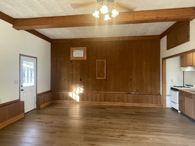 interior space featuring hardwood / wood-style flooring, beamed ceiling, wooden walls, and a textured ceiling