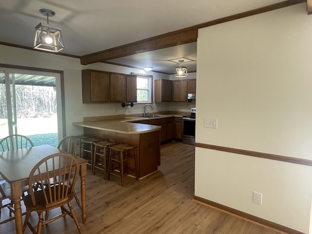 kitchen with stainless steel electric range, dark hardwood / wood-style flooring, hanging light fixtures, a kitchen breakfast bar, and kitchen peninsula