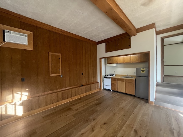 kitchen featuring stainless steel fridge, beam ceiling, wood walls, light hardwood / wood-style floors, and white stove