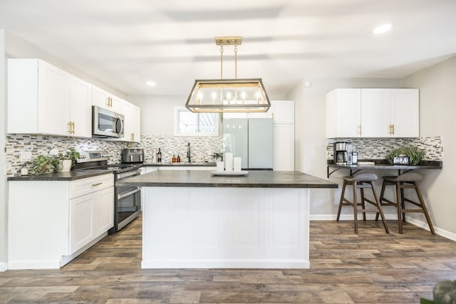 kitchen with white cabinetry, appliances with stainless steel finishes, dark hardwood / wood-style flooring, and hanging light fixtures