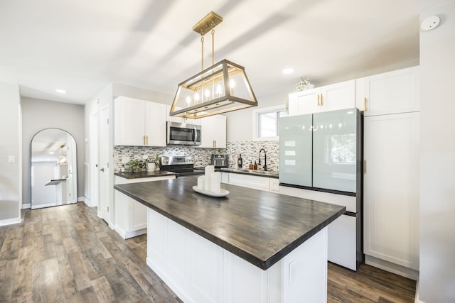 kitchen with a kitchen island, dark hardwood / wood-style floors, white cabinets, decorative light fixtures, and appliances with stainless steel finishes