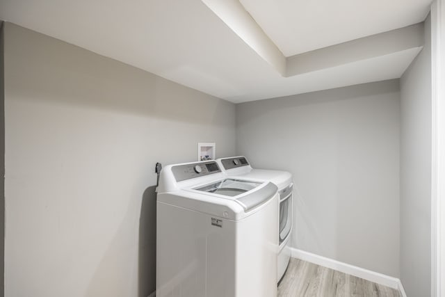 clothes washing area featuring independent washer and dryer and light hardwood / wood-style flooring