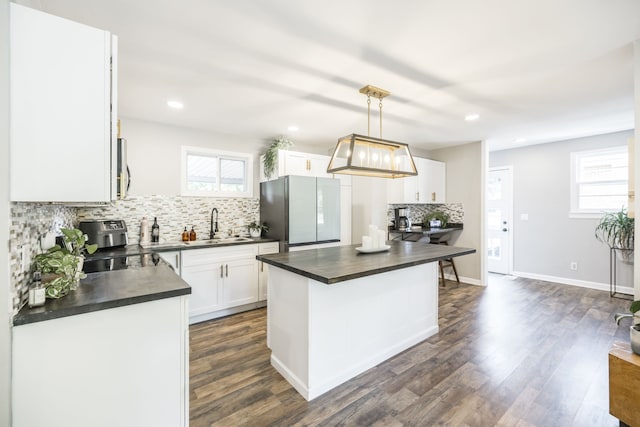 kitchen with white cabinetry, appliances with stainless steel finishes, decorative light fixtures, and plenty of natural light