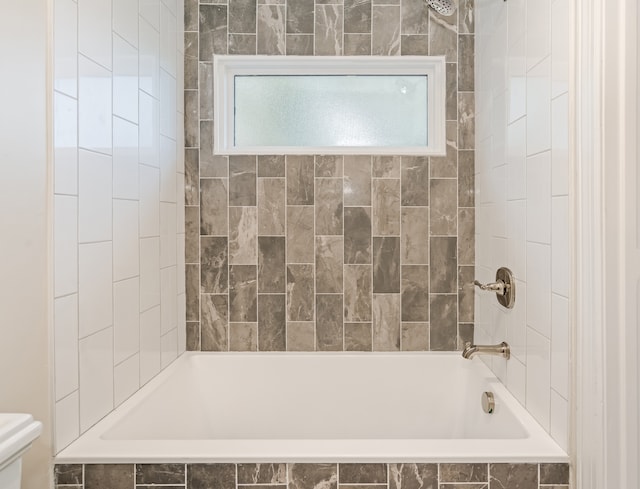 bathroom with toilet and tiled shower / bath