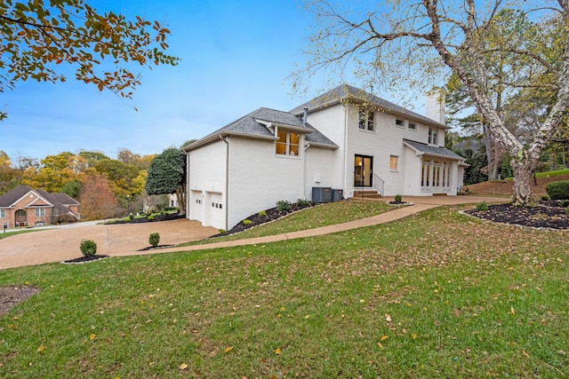 exterior space featuring central AC unit, a garage, and a yard