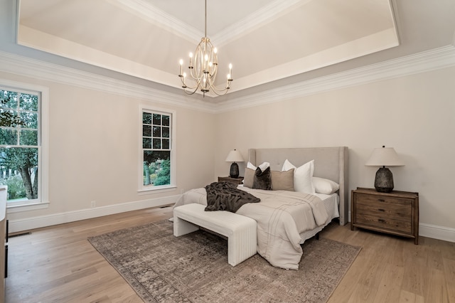 bedroom featuring light wood-type flooring, multiple windows, and a tray ceiling