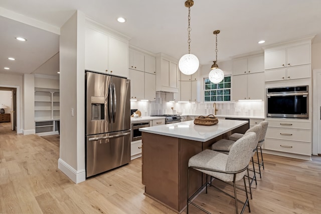 kitchen featuring white cabinets, stainless steel appliances, light wood-type flooring, and a kitchen island