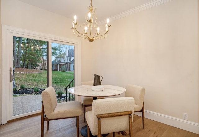 dining room featuring crown molding, light hardwood / wood-style floors, and an inviting chandelier