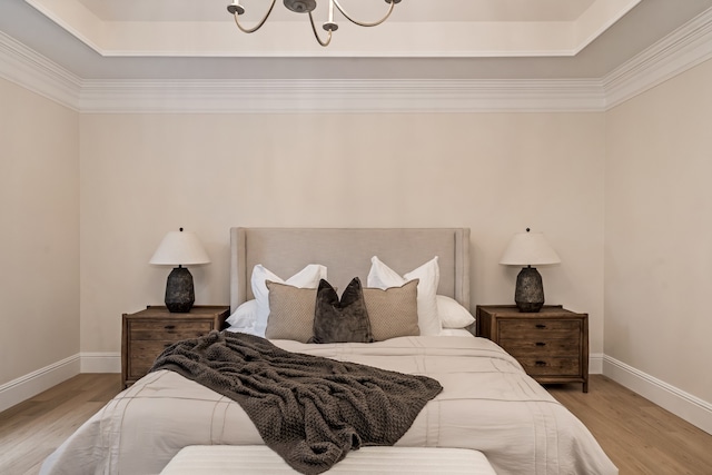 bedroom featuring light wood-type flooring, a tray ceiling, and crown molding