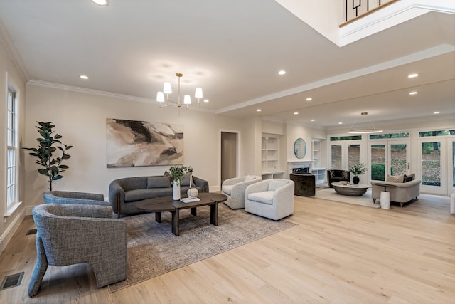 living room with a chandelier, ornamental molding, and light hardwood / wood-style flooring