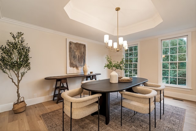 dining room with a chandelier, a tray ceiling, light hardwood / wood-style flooring, and crown molding