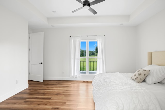 bedroom featuring wood-type flooring, a tray ceiling, and ceiling fan