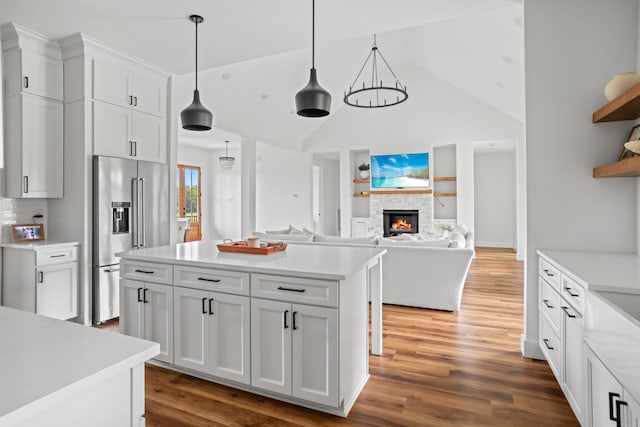 kitchen with high end refrigerator, white cabinets, decorative light fixtures, and dark hardwood / wood-style floors