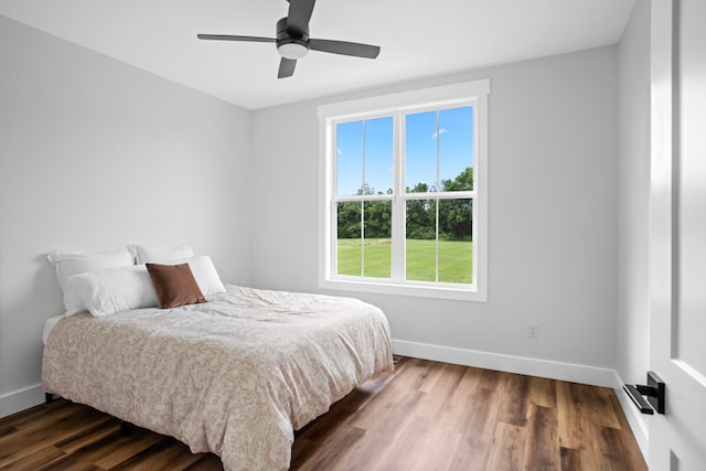 bedroom featuring ceiling fan, multiple windows, and dark hardwood / wood-style floors