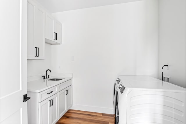 laundry area featuring sink, separate washer and dryer, light wood-type flooring, and cabinets