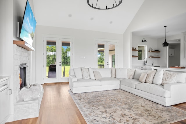 living room featuring sink, french doors, high vaulted ceiling, and light hardwood / wood-style floors