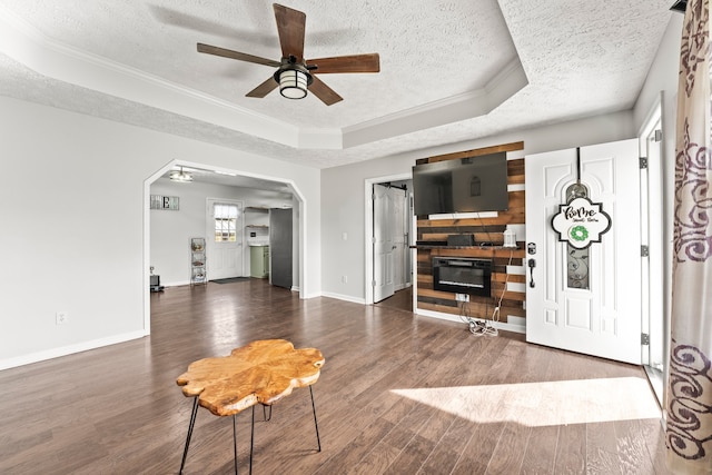 entrance foyer featuring a textured ceiling, dark hardwood / wood-style flooring, ceiling fan, and a raised ceiling