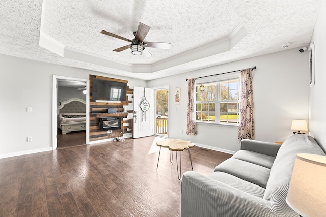 living room featuring ceiling fan, a tray ceiling, a textured ceiling, and dark hardwood / wood-style floors