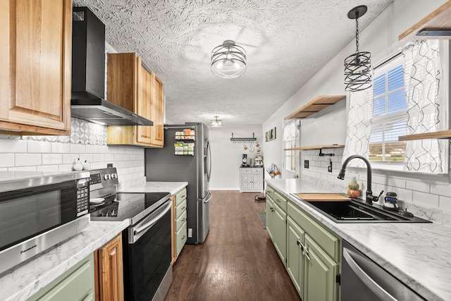 kitchen with wall chimney range hood, appliances with stainless steel finishes, green cabinets, sink, and dark wood-type flooring