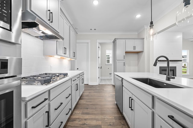 kitchen featuring stainless steel appliances, sink, dark hardwood / wood-style floors, crown molding, and pendant lighting