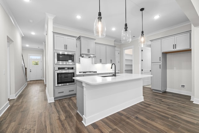 kitchen with an island with sink, dark hardwood / wood-style flooring, decorative light fixtures, and appliances with stainless steel finishes