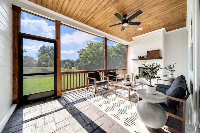 sunroom / solarium with wood ceiling, ceiling fan, and a fireplace