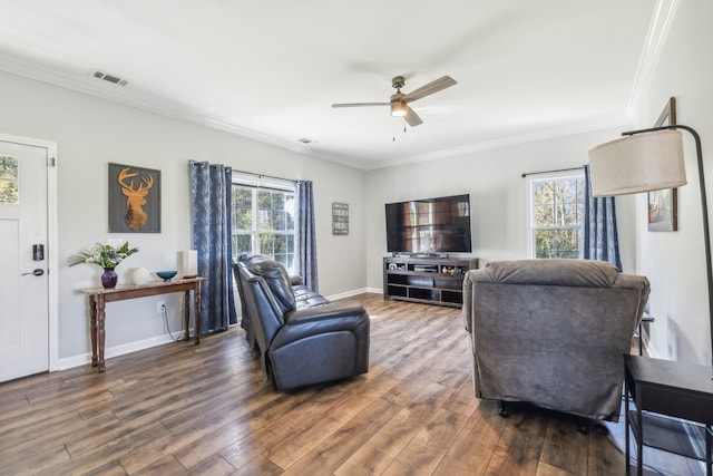 living room featuring baseboards, visible vents, a ceiling fan, ornamental molding, and dark wood-type flooring