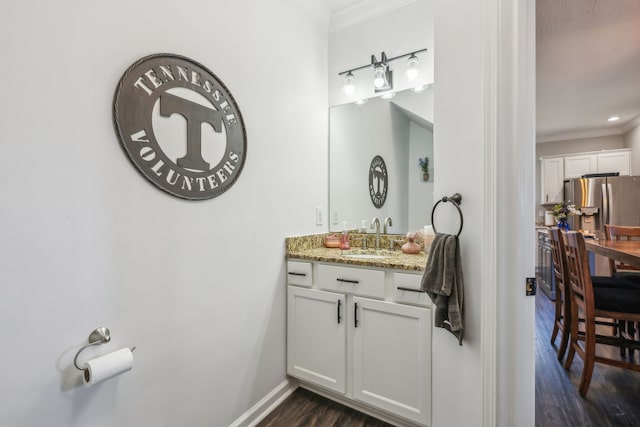 bathroom with ornamental molding, wood finished floors, vanity, and baseboards