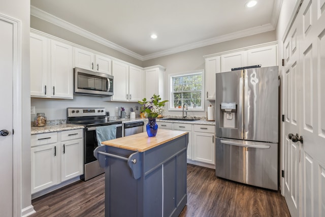 kitchen with dark hardwood / wood-style flooring, white cabinetry, a kitchen island, and appliances with stainless steel finishes