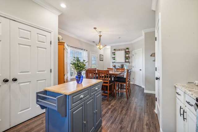 kitchen with dark wood-type flooring, blue cabinetry, butcher block counters, and crown molding