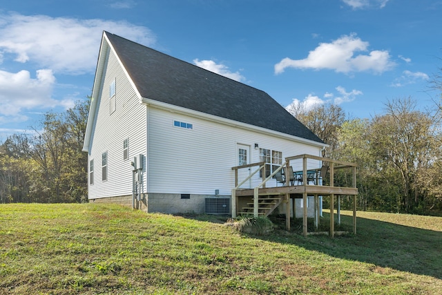 rear view of house with central AC unit, a wooden deck, and a lawn