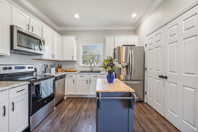 kitchen with appliances with stainless steel finishes, a kitchen island, a sink, and white cabinets