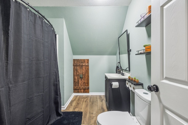 bathroom with hardwood / wood-style flooring, vanity, toilet, and vaulted ceiling