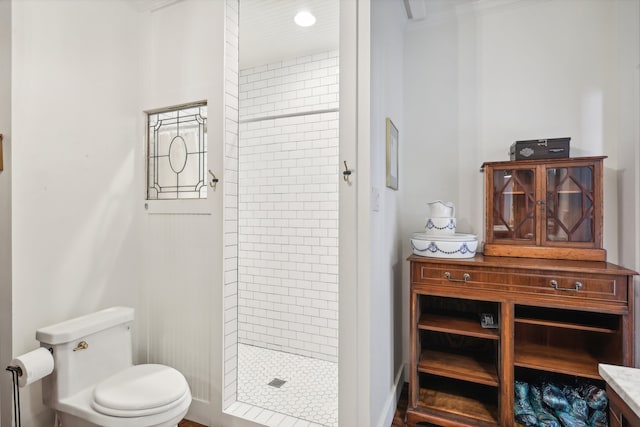 bathroom featuring toilet, ornamental molding, vanity, and a tile shower