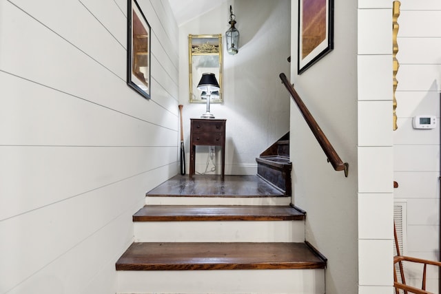 staircase featuring wooden walls