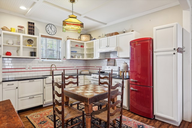 kitchen with white cabinets, stainless steel refrigerator, ornamental molding, dark hardwood / wood-style floors, and white gas range oven